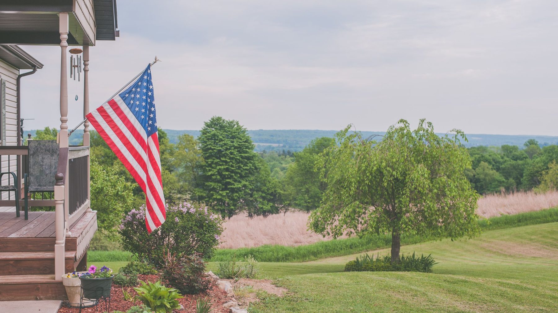 American flag on a porch overlooking a mown lawn